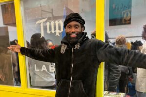 Singer/Rapper Wretch 32 standing in front of the Labrum x Tupac pop up store smiling to camera.