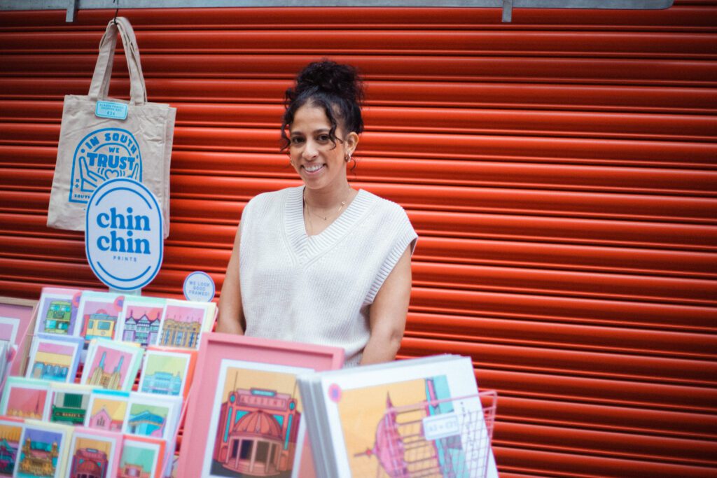 Woman standing behind a stall selling illustrations