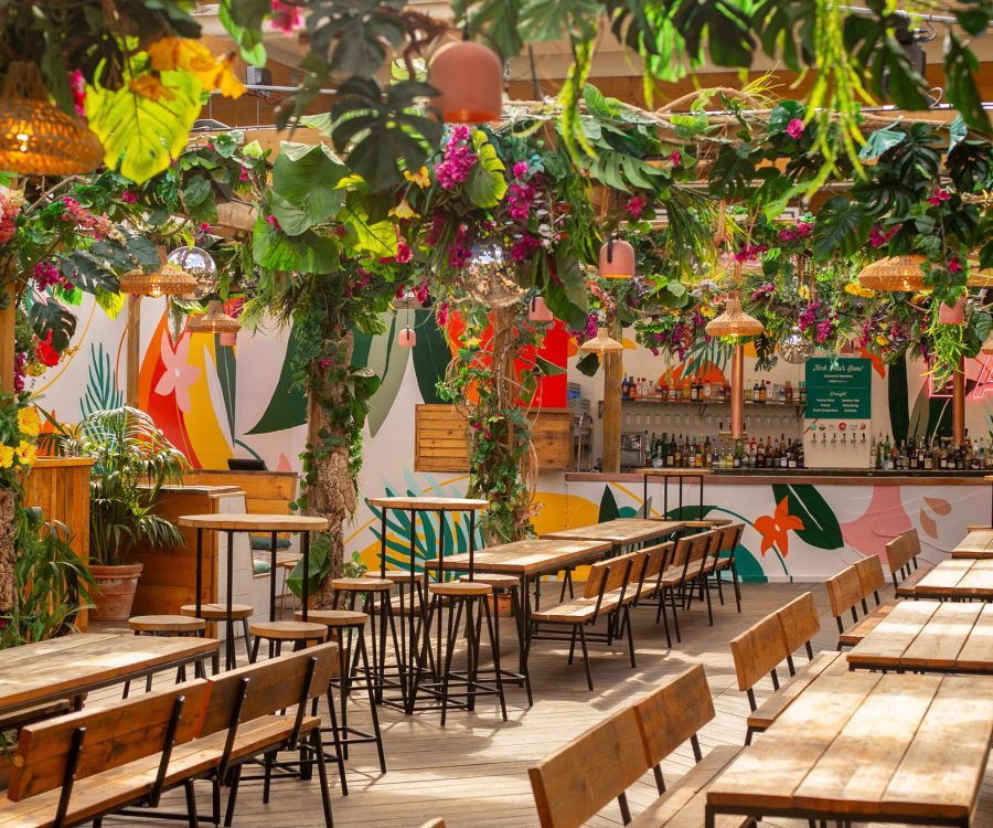 Inside Pergola Brixton rooftop bar, tables and chairs in the sun with floral ceiling decorating