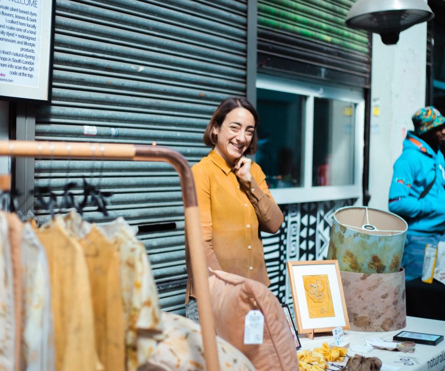 Woman standing behind a stall selling clothing and homeware