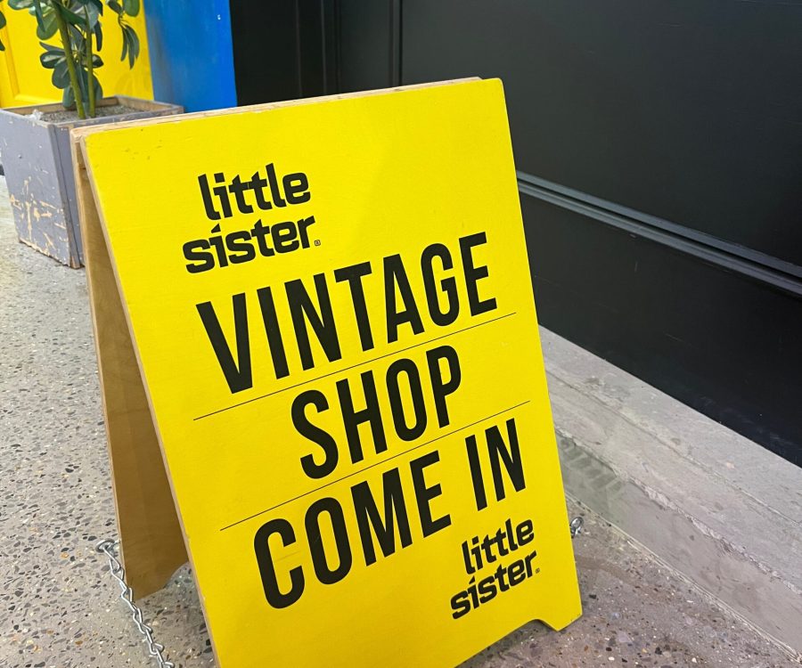 Yellow sign outside door which reads, 'Little Sister Vintage Shop Come In'