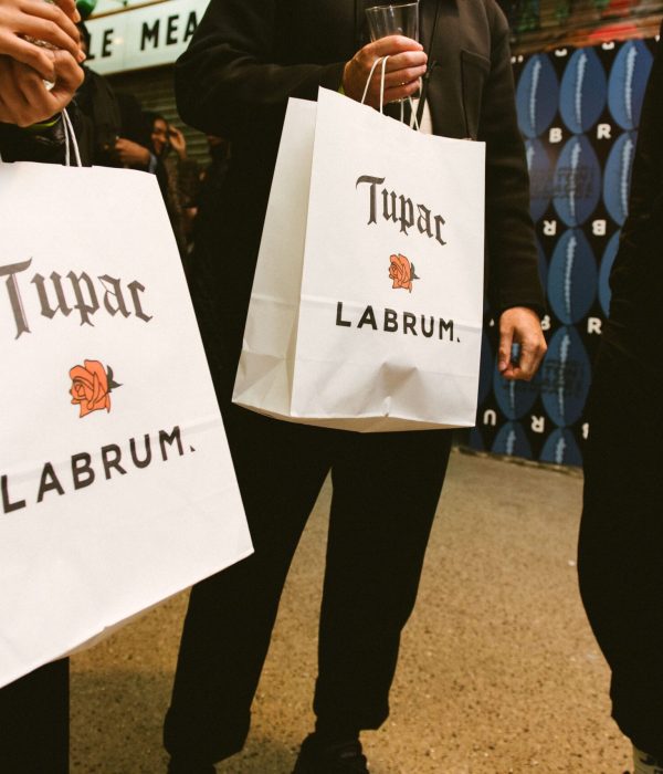 People holding Labrum x Tupac paper bags with clothing inside of them.