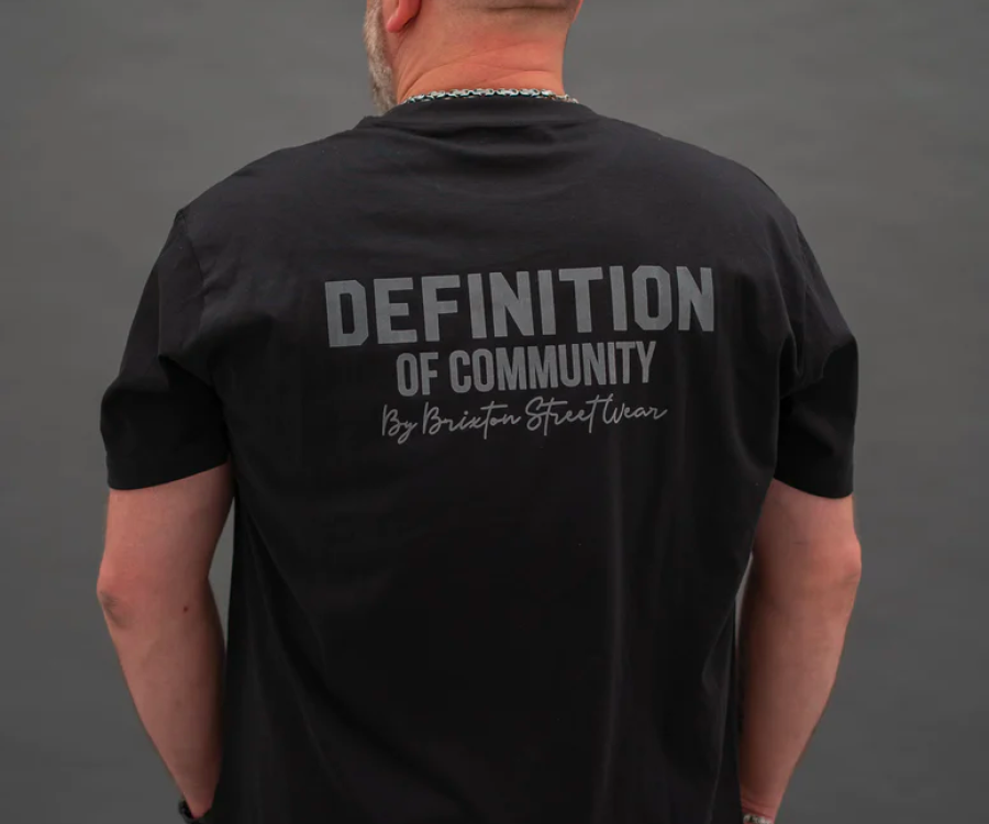 The back of a t-shirt which reads 'Definition of Community. By Brixton Street Wear'.