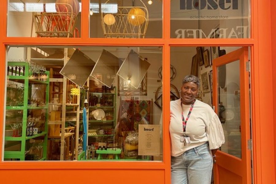 Woman standing in the doorframe of an orange coloured store.