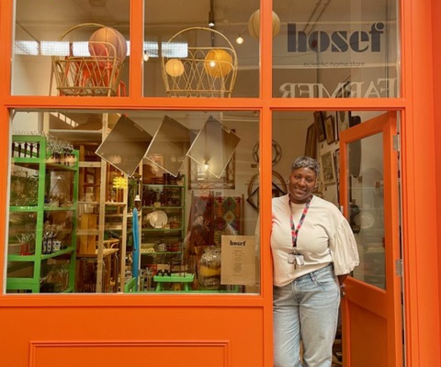 Woman standing in the doorframe of an orange coloured store.