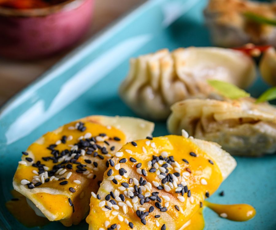 Dumplings covered in a yellow sauce topped with seeds.